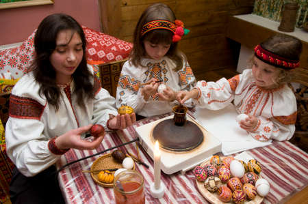 Kolomyia, Ivano-Frankivsk Oblast/Ukraine - 10.07.2008. Family dressed in Ukrainian folk costumes paints eggs for Easter.のeditorial素材