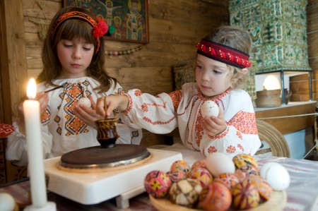Kolomyia, Ivano-Frankivsk Oblast/Ukraine - 10.07.2008. Sisters dressed in Ukrainian folk costumes paints eggs for Easter.のeditorial素材