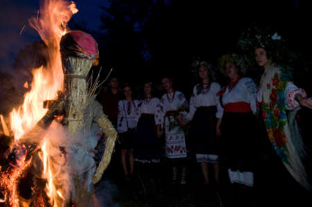 Kiev, Kievskaya Oblast/Ukraine - 07.06.2011. Straw figure of Marena in fire - Ivana Kupala holiday. Woman dressed in traditional slavic (or ukraine) clothes in background.のeditorial素材