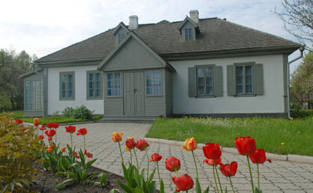 Gray house of Kosachy estate in Kolodiazhne village. Red flowers in foreground.のeditorial素材