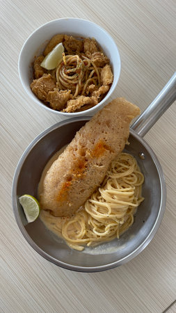 Delicious crispy fish fillet and pasta in a bowl and panの写真素材