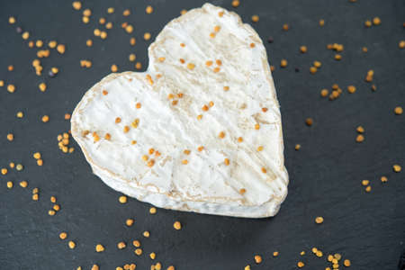 Goat cheese in the shape of a heart with yellow pollen on a black backgroundの写真素材