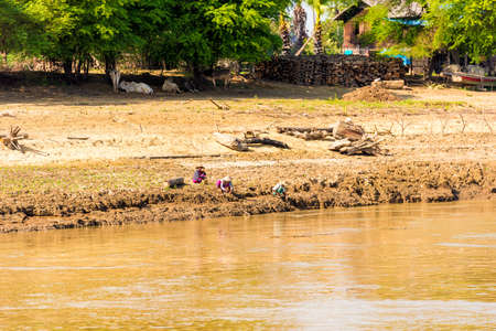 MANDALAY, MYANMAR - DECEMBER 1, 2016: People on the shore in Asian hats, Irrawaddy river, Burma. Copy space for textのeditorial素材