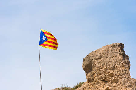 The Spanish flag (Estelada) on the mountain, over blue sky background, Catalunya, Spain. Copy space. Space for textの写真素材