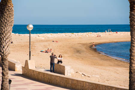 MIAMI PLATJA, SPAIN - APRIL 24, 2017: A man is taking pictures of a woman on the embankment. Copy spaceのeditorial素材
