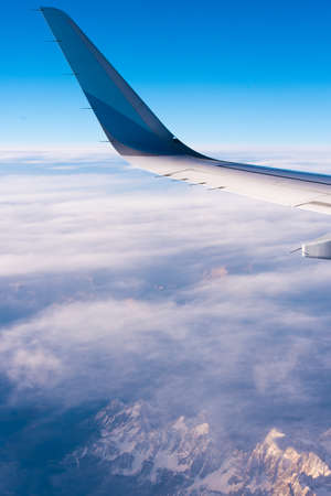 BARCELONA, SPAIN - August 20, 2016: wing of a passenger aircraft, blue sky, clouds and mountains. Copy space. Space for textのeditorial素材