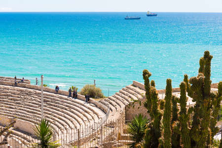 TARRAGONA,SPAIN  MAY 1, 2017: View of the ancient Roman amphitheater and the sea. Cactus in the foreground. Copy space. Space for textのeditorial素材