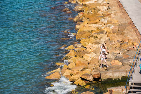 SALOU, TARRAGONA, SPAIN -  APRIL 24, 2017: Girls walk on the rocky beach of the Costa Doradaのeditorial素材