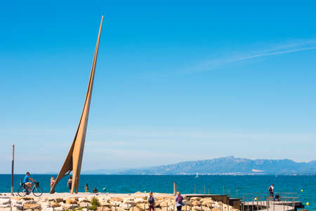 SALOU, TARRAGONA, SPAIN - APRIL 24, 2017: Tourists near the monument on the embankment of the Costa Dorada. Blue sky. Copy space. Space for textのeditorial素材