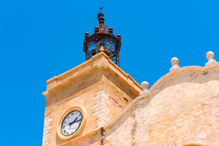 View of the church tower with clock in Sitges, Barcelona, Catalunya, Spain. Isolated on blue backgroundの写真素材