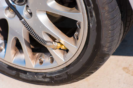 Checking tire pressure. Pumping air into auto wheel. Close-upの写真素材
