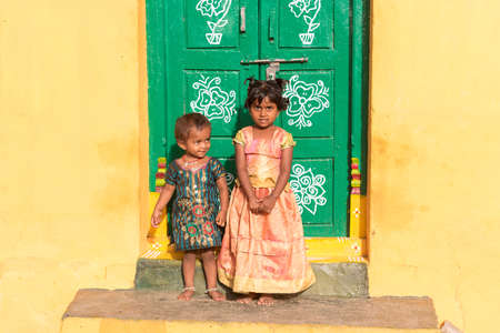 PUTTAPARTHI, ANDHRA PRADESH, INDIA - JULY 9, 2017: Two little indian girls on the doorstep of a house. Copy space for textのeditorial素材