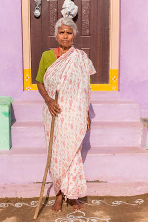 PUTTAPARTHI, ANDHRA PRADESH, INDIA - JULY 9, 2017: An elderly Indian woman at the doorstep of a house. Copy space for text. Verticalのeditorial素材