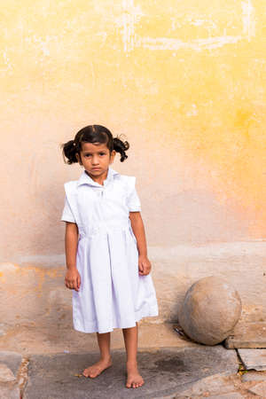 PUTTAPARTHI, ANDHRA PRADESH, INDIA - JULY 9, 2017: Cute Indian girl in white dress. Vertical. Copy space for textのeditorial素材