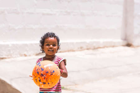 PUTTAPARTHI, ANDHRA PRADESH, INDIA - JULY 9, 2017: Happy indian girl playing on the street. Copy space for textのeditorial素材