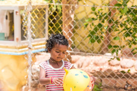 PUTTAPARTHI, ANDHRA PRADESH, INDIA - JULY 9, 2017: Happy indian girl playing on the street. Copy space for textのeditorial素材