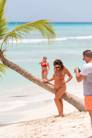 SAONA, DOMINICAN REPUBLIC - MAY 25, 2017: A woman near a palm tree on a sandy beach. Copy space for text. Verticalのeditorial素材