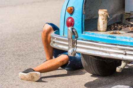 The legs of a man under the car, Vinales, Pinar del Rio, Cuba. Car repairs. Close-upの写真素材