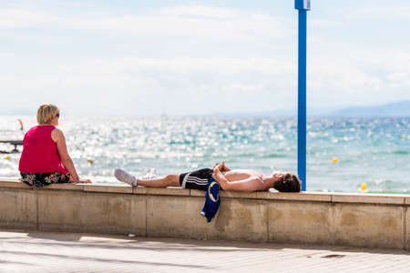 SALOU, TARRAGONA, SPAIN - SEPTEMBER 17, 2017: The man lies on the seafront in Salou. Copy space for textのeditorial素材