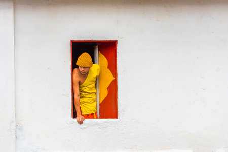 LOUANGPHABANG, LAOS - JANUARY 11, 2017: Monk in the window of the temple. Copy space for textのeditorial素材