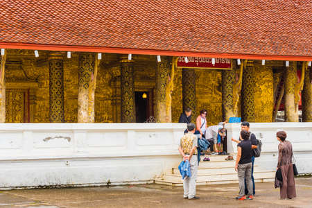 LOUANGPHABANG, LAOS - JANUARY 11, 2017: Tourists near the entrance to the temple. Copy space for text. Verticalのeditorial素材