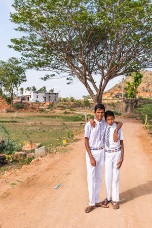 PUTTAPARTHI, ANDHRA PRADESH, INDIA - JULY 9, 2017: Two boys on a rural road. Vertical. Copy space for text.のeditorial素材