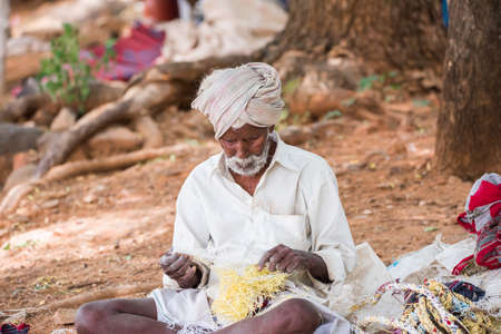 PUTTAPARTHI, ANDHRA PRADESH, INDIA - JULY 9, 2017: Rustic old man in a traditional white dress with a fishing net. Close-upのeditorial素材