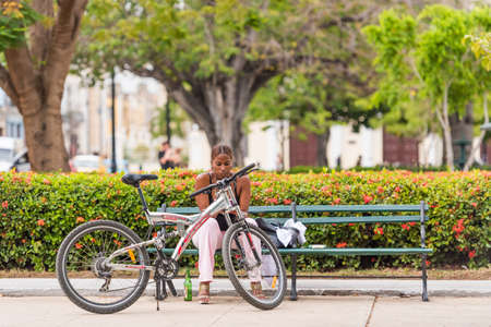 CUBA, HAVANA - MAY 5, 2017: Girl with a bicycle in the park. Copy space for textのeditorial素材