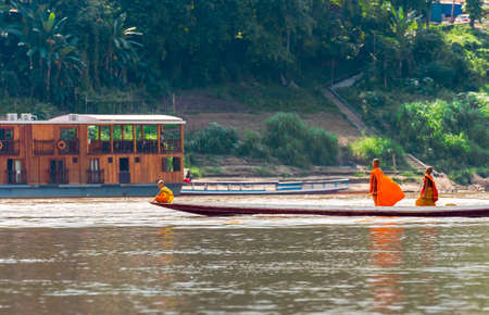 LOUANGPHABANG, LAOS - JANUARY 11, 2017: Monks in a boat on the river Nam Khan river. Copy space for textのeditorial素材