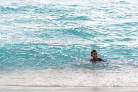PUNTA CANA, DOMINICAN REPUBLIC - MAY 22, 2017:Black boy bathes in the water on the beach. Copy space for textの写真素材