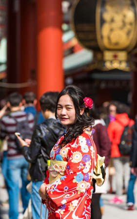 TOKYO, JAPAN - OCTOBER 31, 2017: Girl in a red kimono near the temple Senso-ji. Verticalのeditorial素材