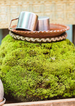 Metal mugs on stone covered with moss in Bagan, Myanmar. Close-up. Verticalの写真素材
