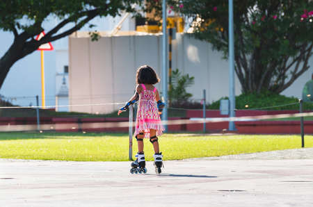 Little girl in a pink dress on roller skates, Male, Maldives. Copy space for textの写真素材