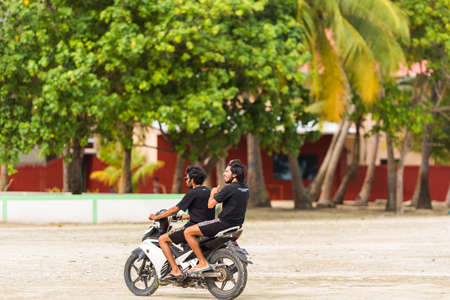 MALE, MALDIVES - NOVEMBER, 27, 2016: Two men riding a motorcycle. Copy space for textのeditorial素材