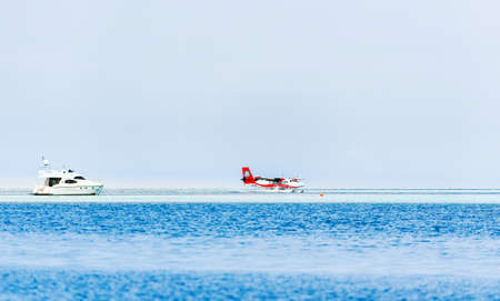 MALE, MALDIVES - NOVEMBER, 27, 2016: Seaplane Trans Maldivian Airways landed on the water. White yacht in the sea. Copy space for textのeditorial素材