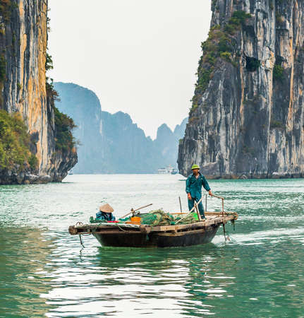 HALONG, VIETNAM - DECEMBER 16, 2016: Fisherman in a boat in the Halong bay. Copy space for textのeditorial素材
