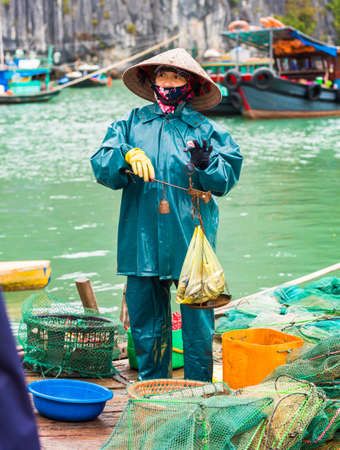 HALONG, VIETNAM - DECEMBER 16, 2016: A woman in the bay sells fish. Vertical. Copy space for textのeditorial素材