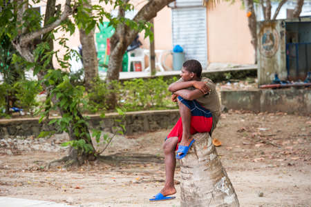 SANTO DOMINGO, DOMINICAN REPUBLIC - AUGUST 8, 2017: A black guy is sitting on a city street. Copy space for textのeditorial素材