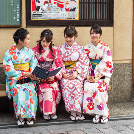 KYOTO, JAPAN - NOVEMBER 7, 2017: A group of girls in a kimono sit on a bench. Copy space for textのeditorial素材