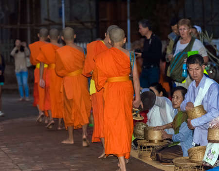 LUANG PRABANG, LAOS - JANUARY 11, 2017: Feeding the monks. The ritual is called Tak Bat. Copy space for textのeditorial素材
