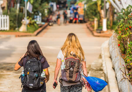 LUANG PRABANG, LAOS - JANUARY 11, 2017: Two girls on a city street. Back view. Copy space for textのeditorial素材