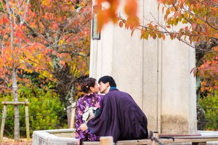 KYOTO, JAPAN - NOVEMBER 7, 2017: A loving couple in a kimono sits on a bench. Copy space for text