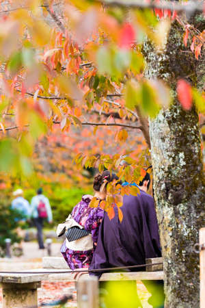 A loving couple in a kimono sits on a bench, Kyoto, Japan. Close-up. Vertical