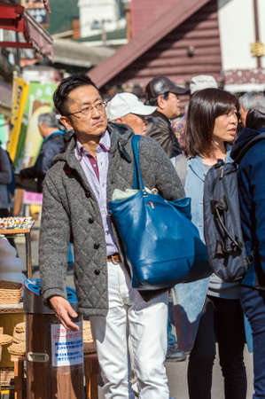 HAKONE, JAPAN - NOVEMBER 5, 2017: A man with a blue bag on a city street. Verticalのeditorial素材