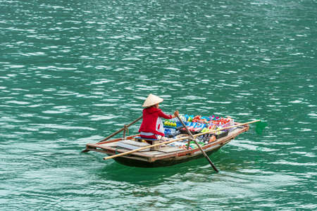 HALONG, VIETNAM - DECEMBER 16, 2016: A woman in a boat with food. Copy space for textのeditorial素材