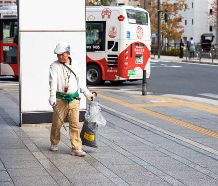 TOKYO, JAPAN - NOVEMBER 7, 2017: A man collects garbage on a city street. Copy space for textのeditorial素材