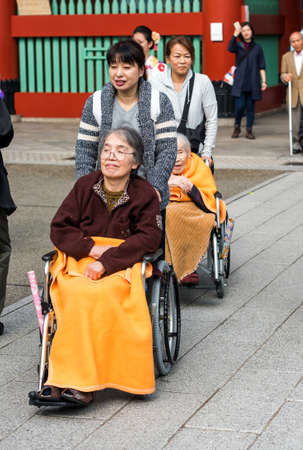 TOKYO, JAPAN - NOVEMBER 7, 2017: Older women in wheelchairs on a city street. Vertical. Copy space for textのeditorial素材