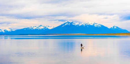 PUERTO NATALES, CHILE - JANUARY 11, 2018: A view of the mountain landscape. A man on board with an oar, sailing on the lake. Copy space for textのeditorial素材