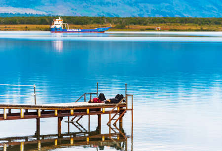 PUERTO NATALES, CHILE - JANUARY 11, 2018: Girls lie on the pier. Copy space for textのeditorial素材