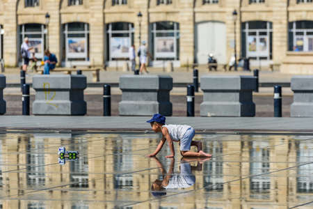 BORDEAUX, FRANCE - MAY 18, 2018: The boy crawls on the Exchange Square. Copy space for textのeditorial素材